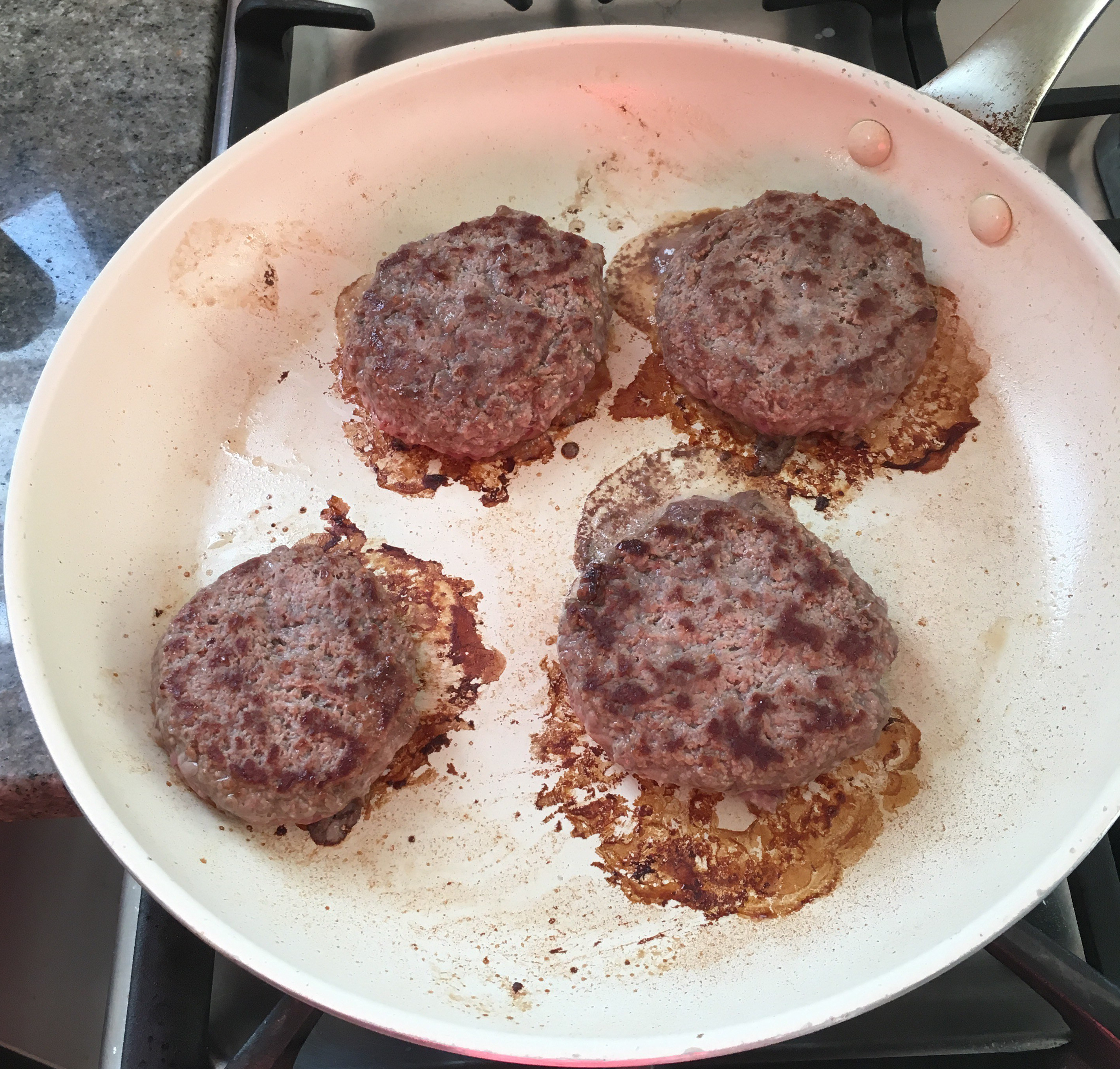Burgers cooking, patties flipped.